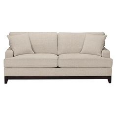 a white couch with pillows on it and a wooden frame around the armrests