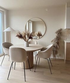 a dining room table with chairs and a round mirror