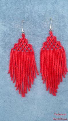 two pairs of red beaded earrings on a blue background