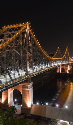 a bridge that is lit up at night with lights on the top and below it