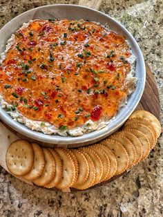 a bowl of dip with crackers on the side