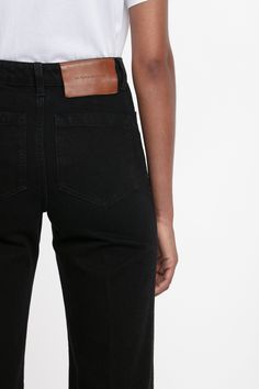 Tailored jeans are integral to the Victoria Beckham brand DNA. Presented exclusively in Washed Black for AW24, the Alina Jean mixes modern references with retro appeal. Seventies-style patch pockets with tonal topstitching are complemented by a branded leather patch at the back of the waist. An antique copper branded denim shank button with contrast red buttonhole and red embroidered Victoria Beckham monogram add discrete but elevated points of difference. Styled with the Victoria T-Shirt Victor Designer Black Straight Leg Jeans, Classic Black Flare Jeans With Pockets, Classic Black Flare Jeans For Office, Classic Black Flare Jeans For Work, Modern Black Flare Jeans, Luxury Bottoms With Five Pockets, Designer Fitted Straight Leg Jeans, Luxury Black Jeans With Five Pockets, Modern Black Jeans For Workwear