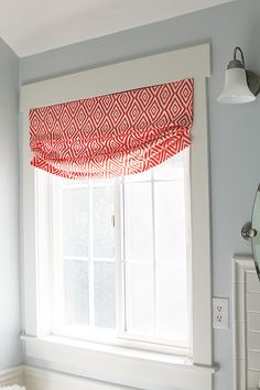 a window with a red and white valance hanging from it's side in a bedroom