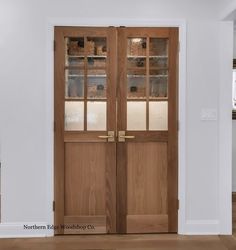 an empty room with two wooden doors in the center and shelves on the wall behind them