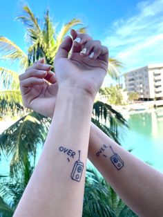 two people holding hands with tattoos on their arms, one has a camera and the other has a radio