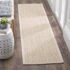 a white rug on the floor next to a potted plant