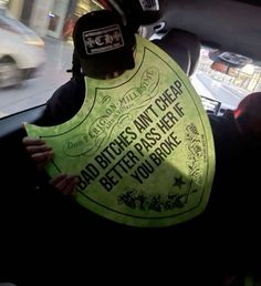 a person in a car wearing a bib and hat with an anti - cheap sign on it