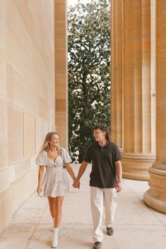 a man and woman holding hands while walking through an archway