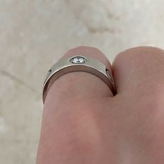 a person's hand wearing a ring with a diamond in the middle on it