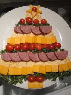 a christmas tree made out of cheese and ham on a plate with tomatoes, lettuce