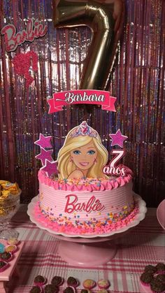 a barbie birthday cake with pink icing and stars on it, surrounded by cupcakes