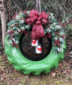 a christmas wreath on top of a green tire in front of a chain link fence