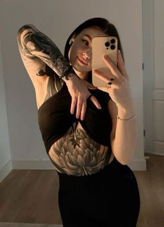 a woman taking a selfie with her cell phone in front of her face and tattoos on her arm