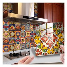 a hand holding up a piece of paper in front of a colorful tile backsplash