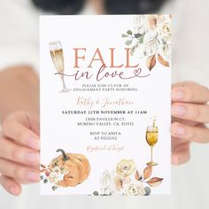 a woman holding up a fall in love party card with flowers and wine glasses on it