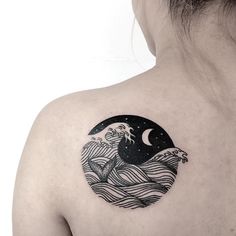 the back of a woman's shoulder with an image of a wave on it