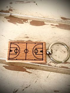 a wooden keychain with a basketball court on it