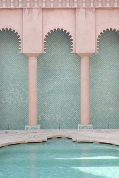 an empty pool in front of a wall with arches