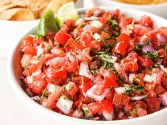 a close up of a bowl of food with bread in the background and salsa in the foreground