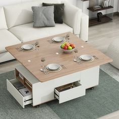 a coffee table with plates and bowls on it in front of a white sectional couch