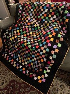 a couch with a quilt on it and a chair in the back ground next to it