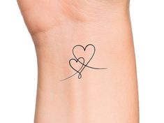 a small tattoo on the wrist of a woman's arm with two hearts in it