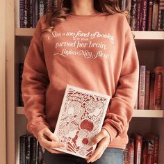 a woman standing in front of a bookshelf holding a book with the words she is god of books on it