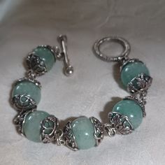 Gorgeous Stephen Dweck Aventurine Beaded Bracelet. This Piece Has 6 Gorgeous And Large Aventurine Beads That Are Surrounded By Decorative Sterling In A Leaf And Floral Design. The Beads Are Half An Inch Wide. This Piece Has A Toggle Closure. The Toggle Is Stamped Inside Stephen Dweck Sterling. This Piece Is In Excellent Pre-Owned Condition. The Green Is A Beautiful Shade That Has Some Cream And Grey Color Through It. This Would Be Fabulous Alone Or Stack It With Other Fun Pieces. Silver Amazonite Bracelet As Gift, Silver Amazonite Bracelet For Gift, Handmade Silver Amazonite Beaded Bracelets, Silver Jade Beaded Bracelets With Gemstones, Silver Jade Beaded Bracelets, Silver Jade Beaded Bracelets With Gemstone Beads, Silver Beaded Jade Jewelry, Silver Jade Beaded Bracelets With Natural Stones, Silver Jade Beaded Bracelet With Natural Stones