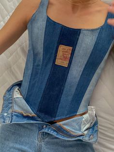 a woman wearing a blue jean corset laying on top of a bed