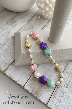 a bracelet with seashells and starfish beads on it, sitting next to a vase