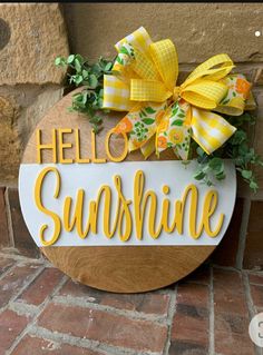 a wooden sign that says hello sunshine on the side of a building with yellow bows