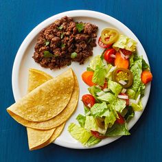 a white plate topped with lettuce, salad and tortilla wedges