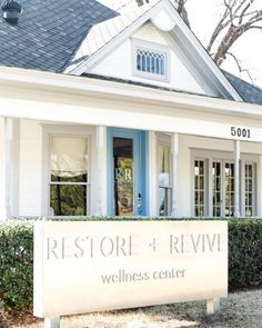 a white house with a blue front door and sign that says restore + rivin