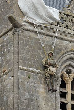 a man hanging from the side of a tall building while holding onto a white tarp