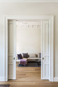 an open door leading to a living room with white walls and wood floors, along with a couch