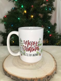 a white coffee mug sitting on top of a wooden table next to a christmas tree