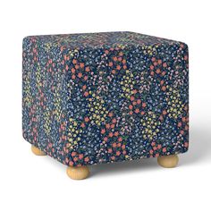 an ottoman cover with colorful flowers on it and wooden legs in front of white background