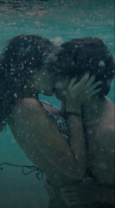 a man and woman kissing under water in the ocean with bubbles coming off their backs