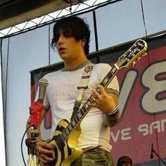 a man holding a guitar while standing on top of a stage