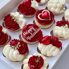 a box filled with cupcakes covered in white frosting and red icing