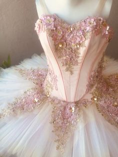 a pink and gold ball gown with flowers on the bouncy, in front of a mannequin