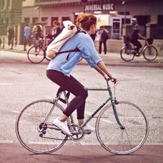 a woman riding a bike down the street