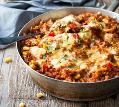 a casserole dish with meat, cheese and vegetables in it on a wooden table