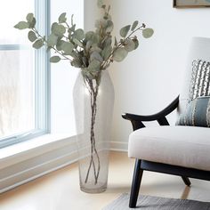 a vase filled with flowers sitting on top of a wooden floor next to a chair