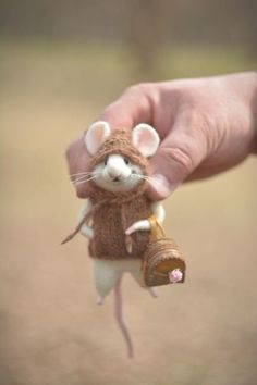 a hand holding a small toy mouse in it's right hand with a bell attached to it