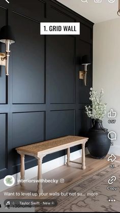 a bench sitting in front of a black wall next to a vase with flowers on it