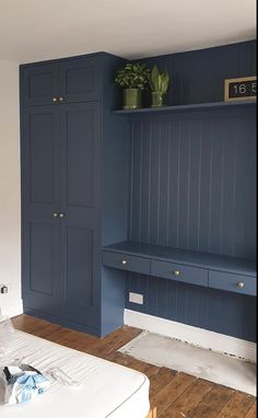 a bedroom with blue painted walls and wooden flooring, built in to the wall