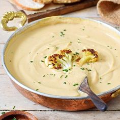 there is a bowl of soup with broccoli in it and bread on the side