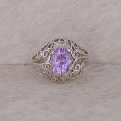 This ladies sterling silver ring has an oval 8x6mm lavender cubic zirconia that is prong set at the center. The silver mounting has filigree designs around the ring and it weighs 2.33 grams. The finger size of the ring is 5.25. Condition: Pre-Owned *All items are thoroughly inspected for quality assurance purposes Purple Oval Amethyst Ring With Filigree, Oval Purple Amethyst Ring With Filigree, Oval Purple Filigree Amethyst Ring, Purple Oval Filigree Rings, Silver Amethyst Ring With Intricate Design, Oval Purple Filigree Ring As Gift, Purple Oval Filigree Ring As A Gift, Purple Oval Filigree Ring For Anniversary, Purple Oval Filigree Ring For Gift