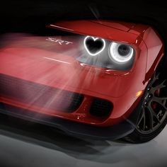 a red sports car with heart eyes on it's hood and headlights in the dark